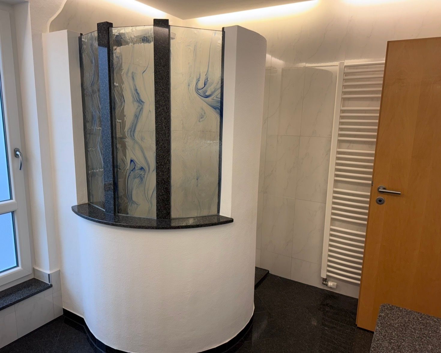 Gemauerte, runde Dusche mit Glaselementen und Granitabdeckung in einem renovierten Bad